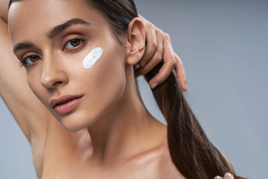 Cute young lady applying facial Day Moisturizers with SPF		
. Beauty procedures concept